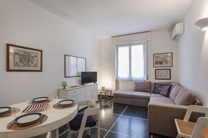 Un ambiente compatto con zona pranzo, divano e televisione.