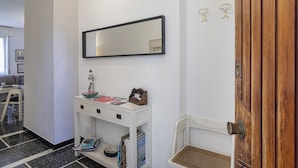 A hallway with a white console table, a mirror, and a wooden door. - S Margherita Harbour Apartment by Wonderful Italy (Santa Margherita Ligure)