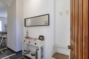 Un corridoio con una consolle bianca, uno specchio e una porta in legno.