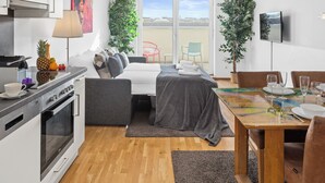 Ein modernes, helles Zimmer mit einer Küchenzeile, einem Essbereich und einem Bett.