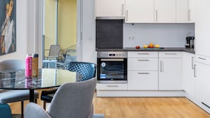 Eine moderne Küche mit weißen Schränken, einem eingebauten Backofen und einer Kaffeemaschine.