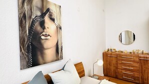 Un dormitorio con una cama, un aparador, un espejo y un cuadro colgado en la pared.