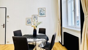 Una habitación con una mesa de comedor, sillas, un jarrón con flores y cuadros en la pared.