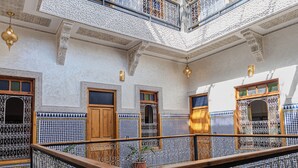 A multi-level interior with ornate metal railings, tiled floors, and detailed wall designs. - Riad Al Mozyane (Fès)
