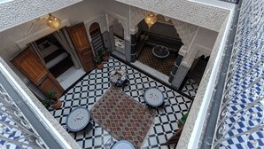 A courtyard with a checkered floor, a central rug, and two round tables. - Riad Al Mozyane (Fès)