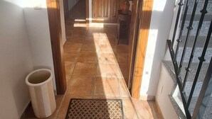 Un couloir carrelé qui mène à une porte en bois.