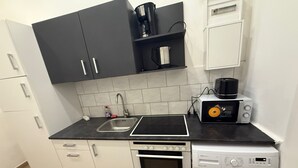 Une cuisine compacte équipée d’un four à micro-ondes, d’un grille-pain, d’un four et d’un lave-linge.