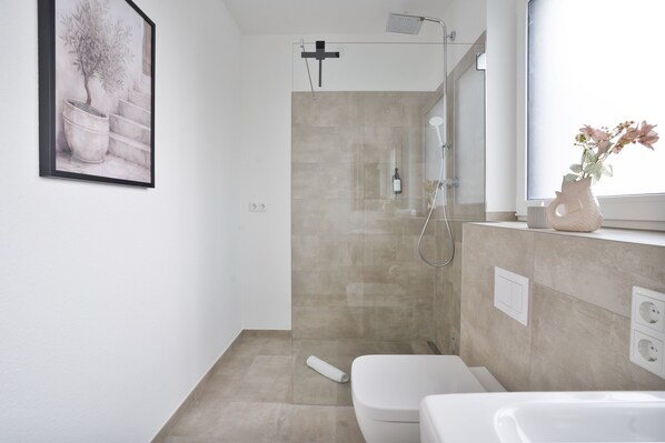 Un baño moderno con ducha, inodoro y lavamanos.