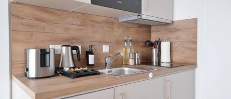 Deluxe appartement, balkon | Privékeuken | Een koelkast, een magnetron, een kookplaat, kookgerei, borden en bestek