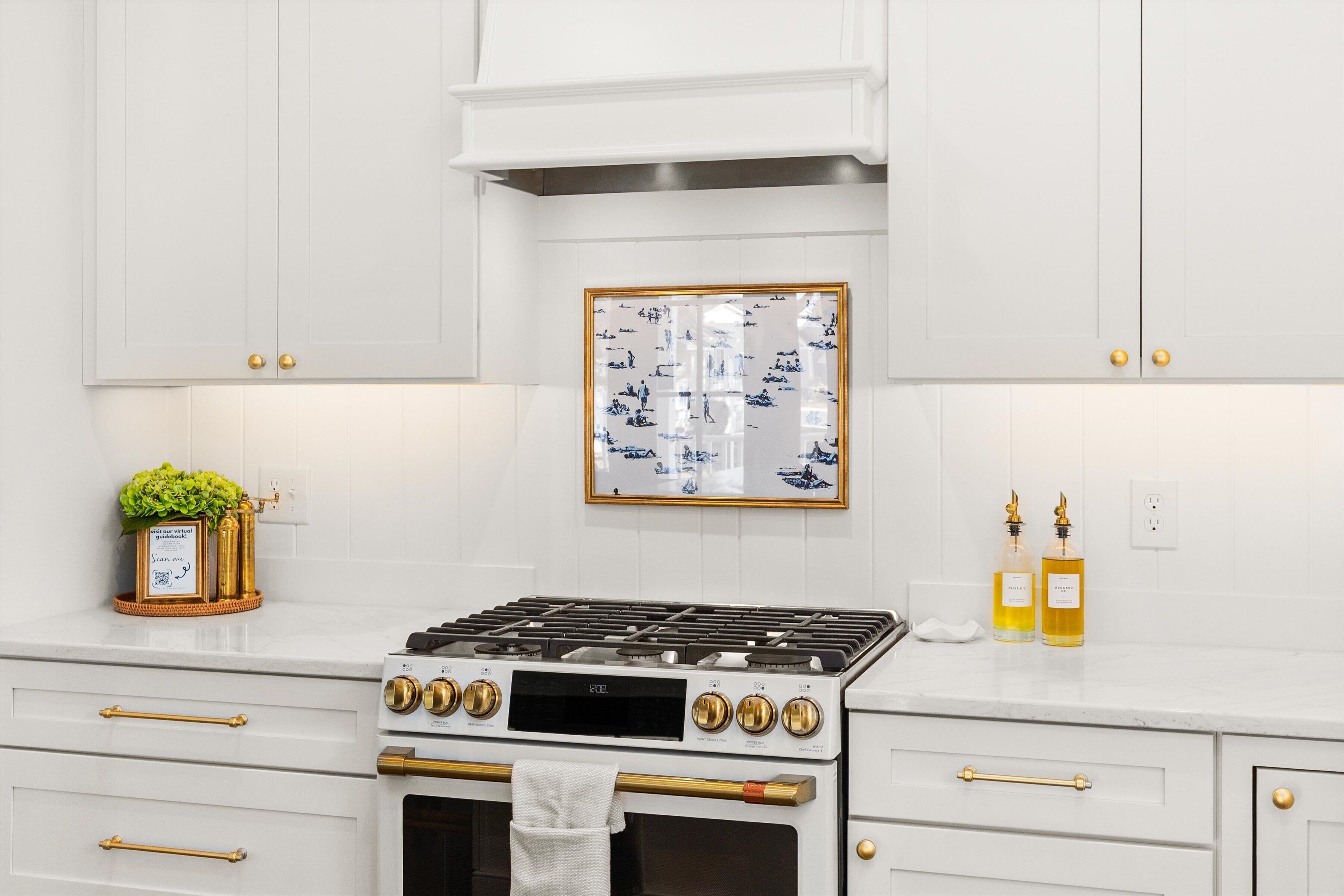 Une cuisine avec des meubles blancs, une cuisinière et deux bouteilles d’huile posées sur le comptoir.