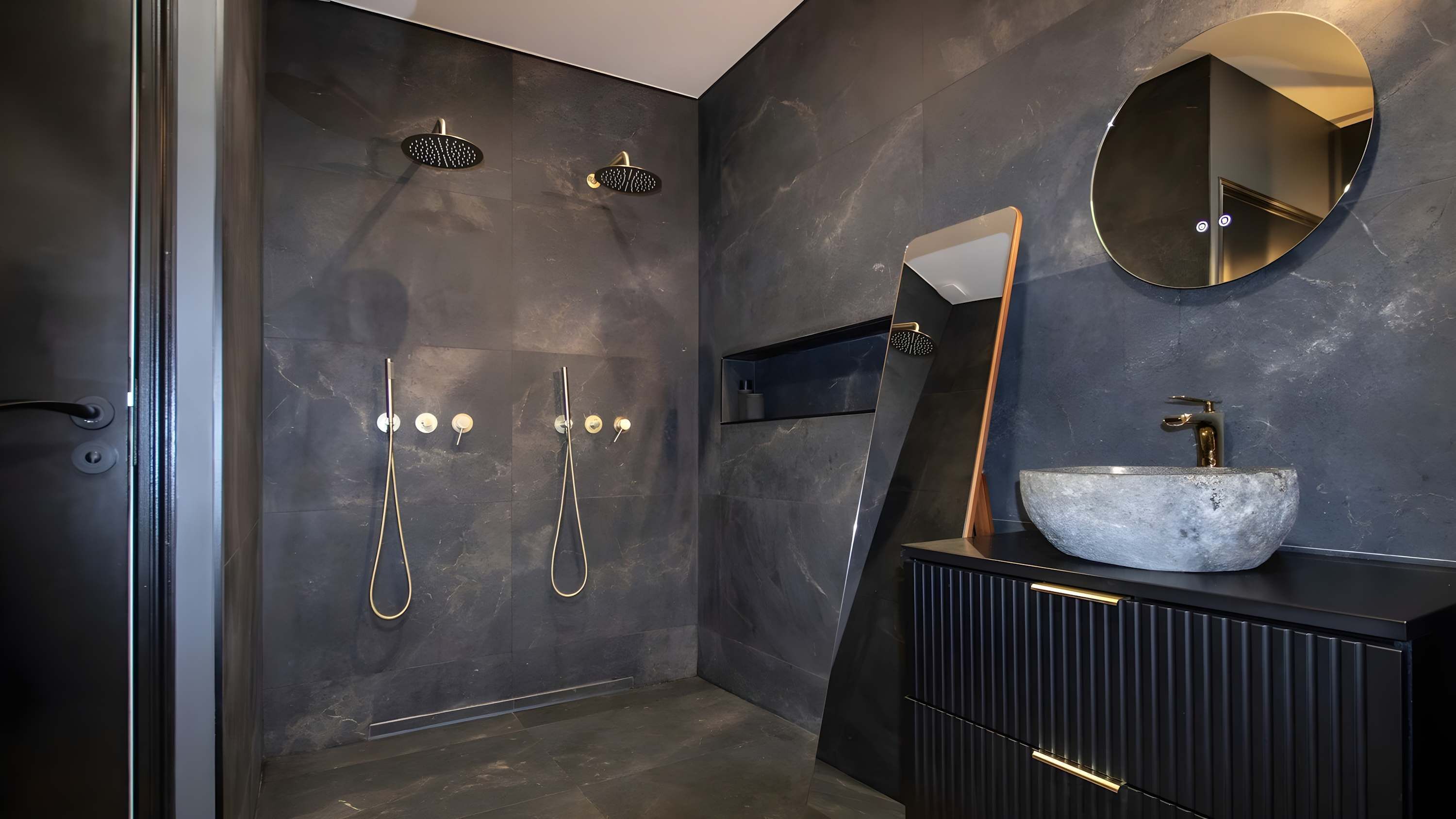 A modern bathroom with a large mirror, a vessel sink, and two showerheads.