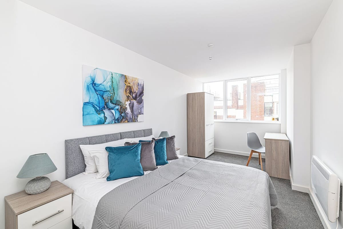 A modern bedroom with a bed, a desk, and a chair.