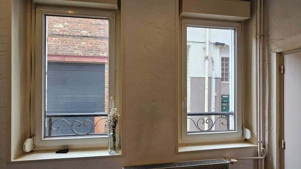 Two windows with metal railings, a radiator below the windows, and a brick wall visible through the windows. - Petit rez-de-chaussée du théâtre (Arras)
