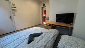 A bedroom with a bed, a TV, a desk, and a wardrobe. - Petit rez-de-chaussée du théâtre (Arras)
