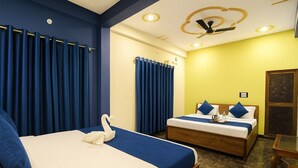 Habitación de hotel con dos camas, un ventilador de techo y una mesa de madera.