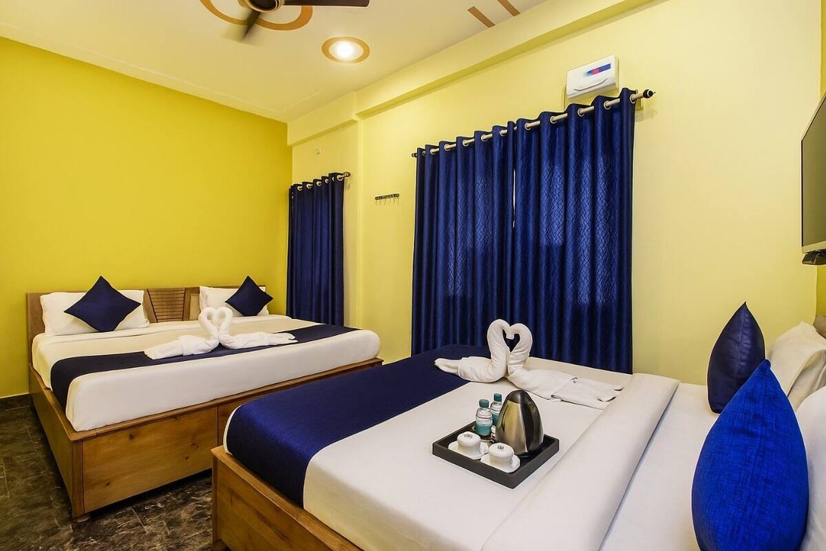 Une chambre d’hôtel avec deux lits, chacun agrémenté de draps et d’oreillers bleus, et un plateau avec des articles de toilette posé sur l’un des lits.