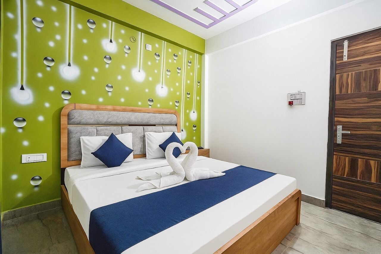 A hotel room with a bed, a green wall, and a wooden door.