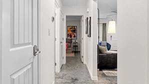 A hallway with white doors, a gray tiled floor, and a sofa with cushions.