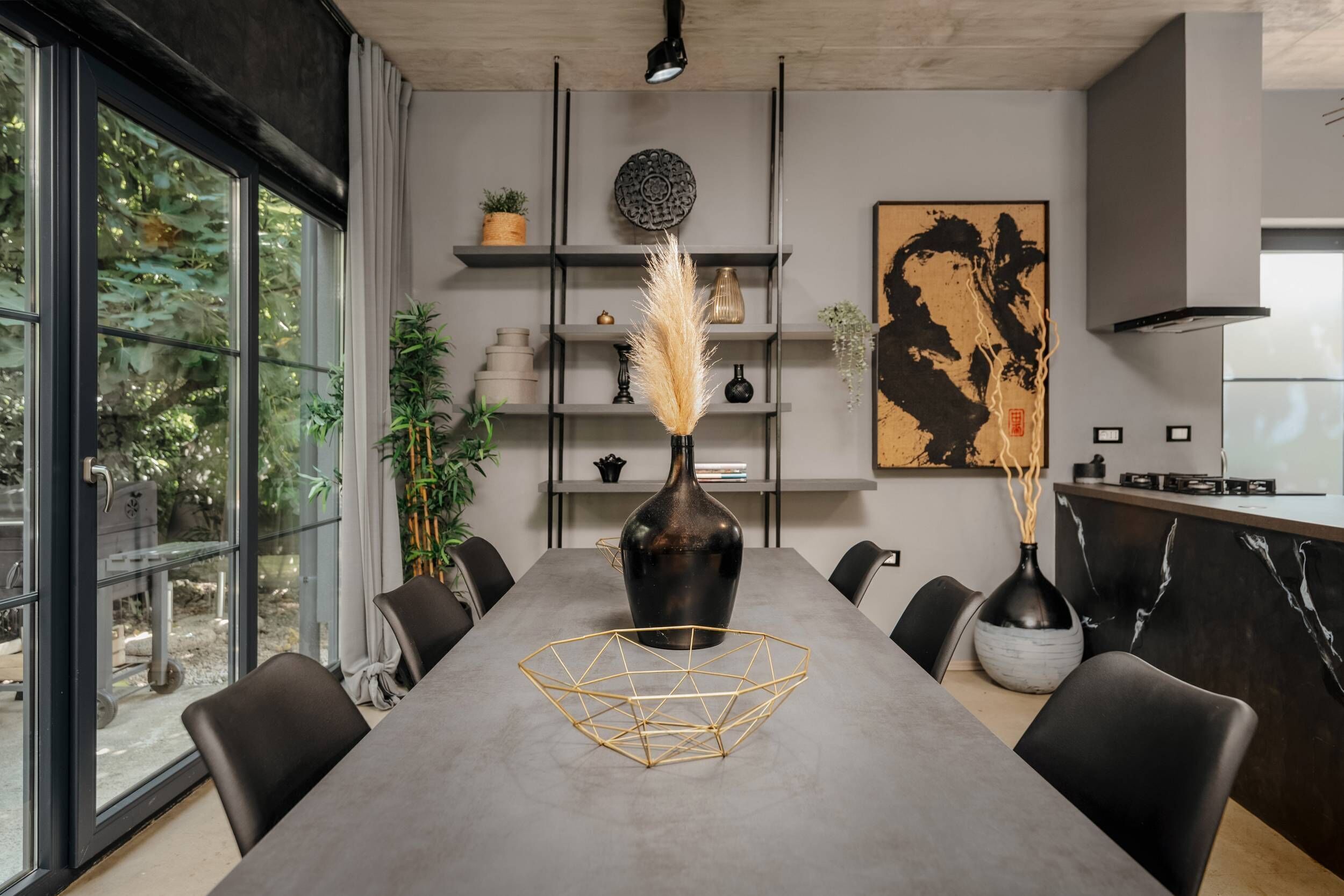 A modern dining area with a long table, chairs, and decorative vases.