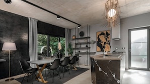 Una cocina moderna con una isla de mármol, sillas negras y una mesa de comedor.
