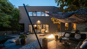 Un patio exterior moderno con piscina, zona de estar y un edificio al fondo.