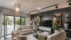 Una sala de estar moderna con un televisor grande, asientos cómodos y vistas al exterior.