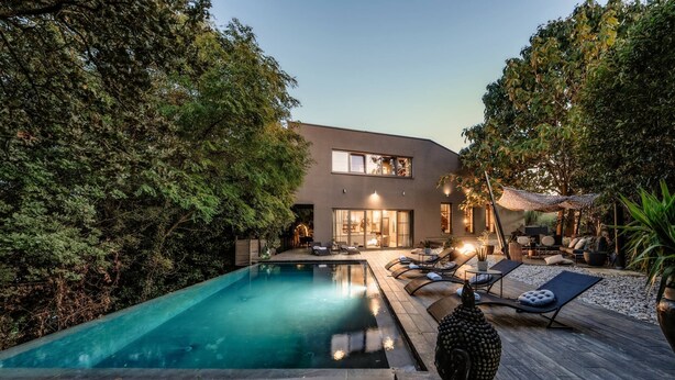 Una casa moderna con piscina, sillas de descanso y terraza.