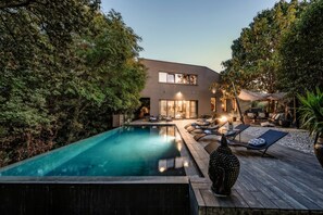 Una casa moderna con piscina, sillas de descanso y terraza.
