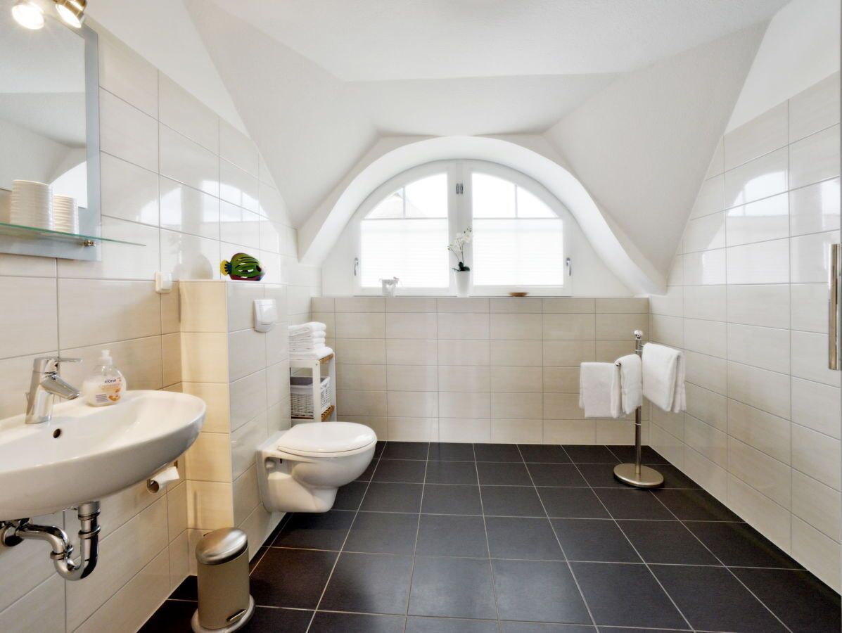 A modern bathroom with a white sink, toilet, and a towel rack.