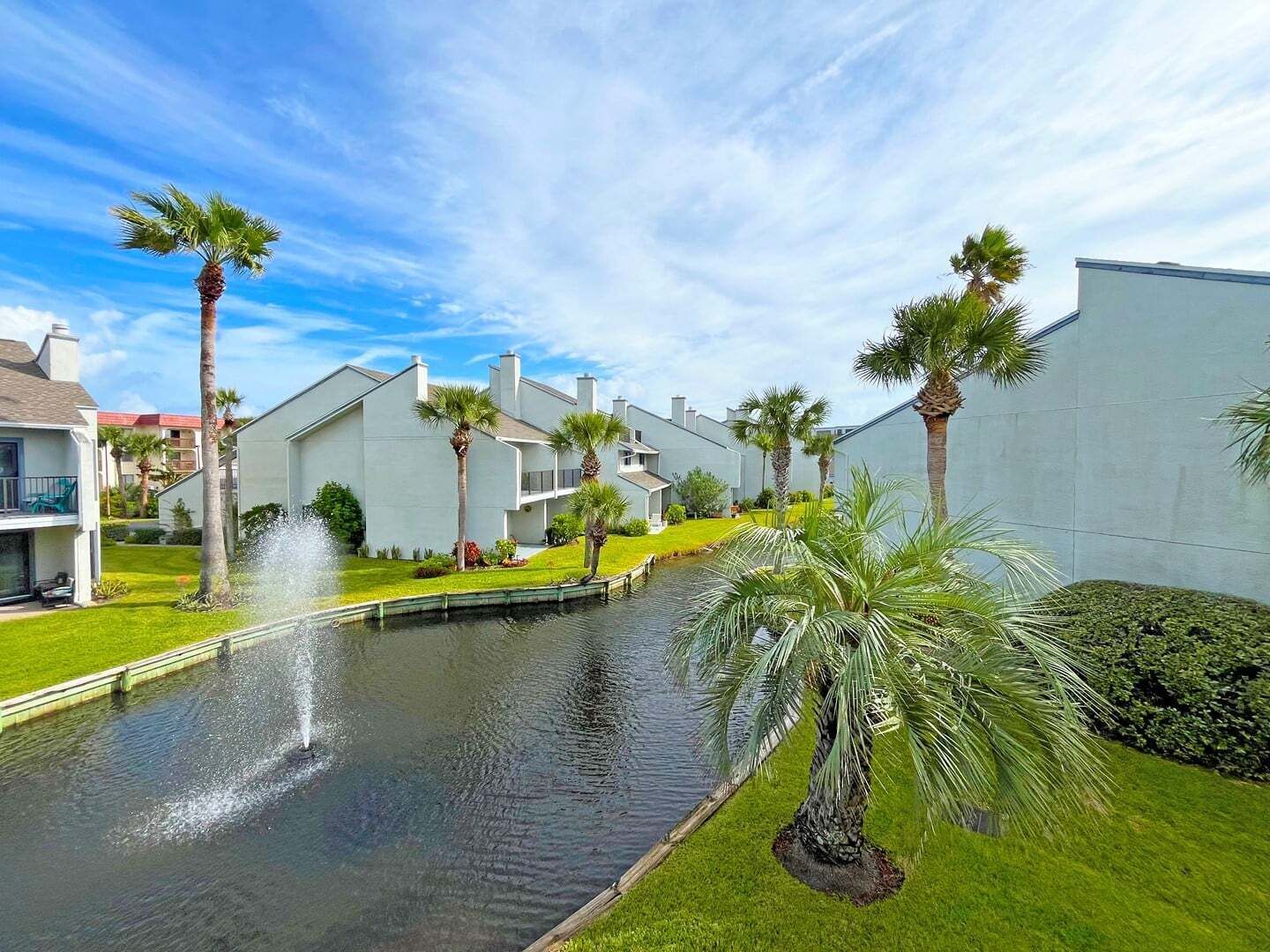 A residential area with a canal, palm trees, and modern houses.