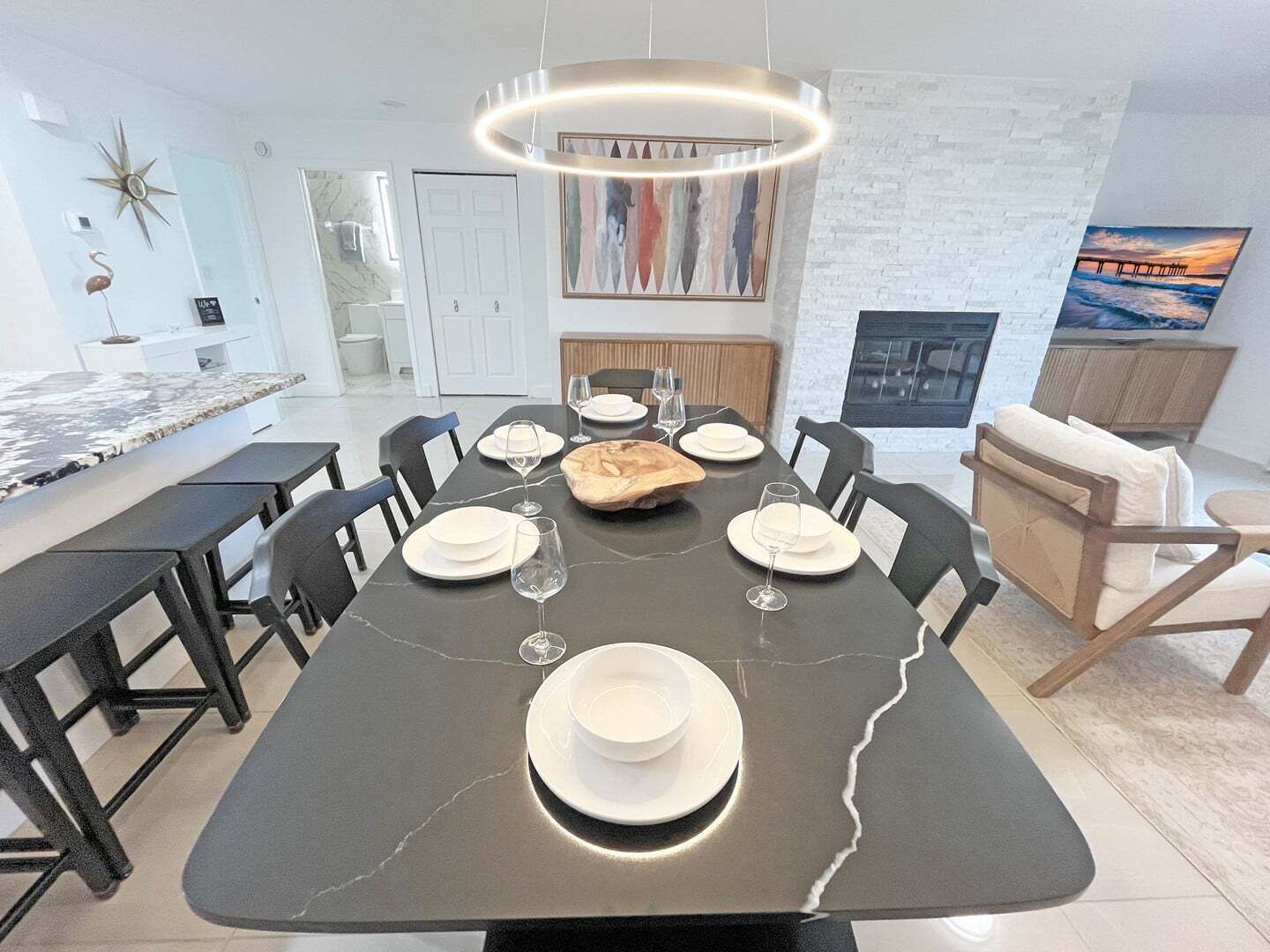 A modern dining area with a marble table, black chairs, and a central light fixture.
