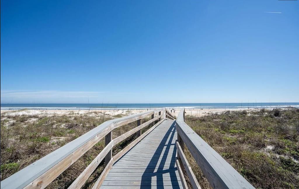 A wooden boardwalk leading to a beach with clear skies.