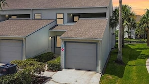 Ein modernes, zweistöckiges Haus mit Garage, überdachter Auffahrt und gepflegtem Rasen mit Palmen.