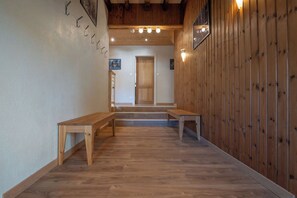 Un couloir doté d’un plancher en bois, de bancs et d’une porte au fond.