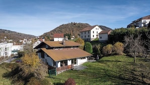 Un quartier résidentiel avec des maisons, une colline verdoyante et une montagne en arrière-plan.