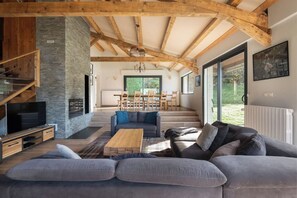 Een ruime woonkamer met een moderne open haard, een grote bank en een eettafel.