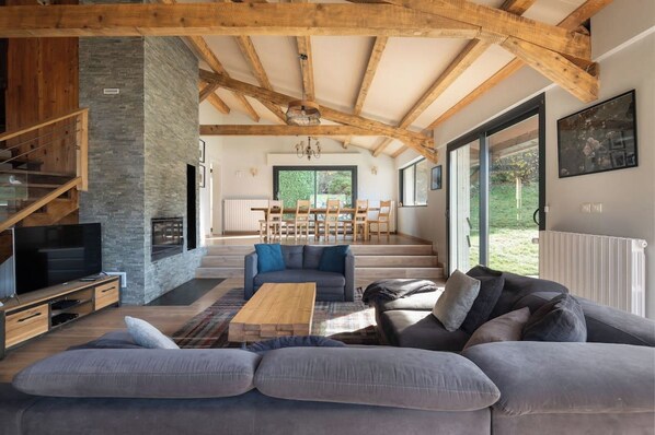 A spacious living area with a modern fireplace, a large sofa, and a dining table.
