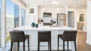 Une cuisine moderne dotée d’un îlot central, de tabourets de bar et de luminaires suspendus.