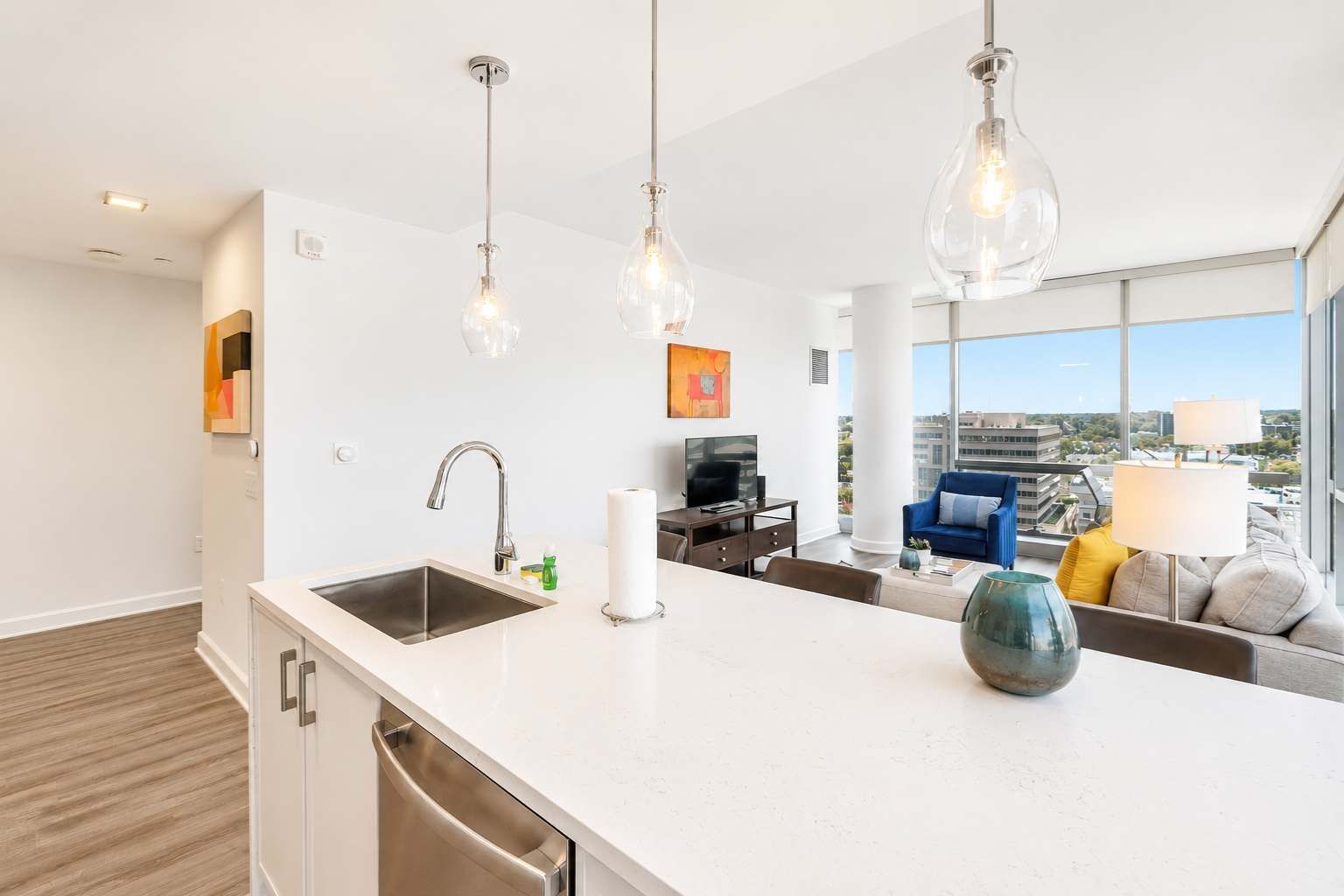 A modern kitchen with a large island, stainless steel appliances, and pendant lighting.