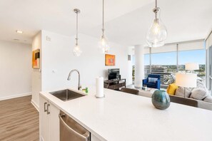 A modern kitchen with a large island, stainless steel appliances, and pendant lighting.
