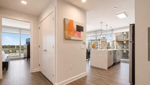 Un appartement moderne doté d’un îlot de cuisine, d’un coin repas et d’une grande fenêtre offrant une vue sur la ville.