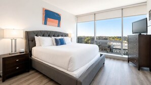 Une chambre d’hôtel moderne équipée d’un grand lit, d’une table de chevet, d’une commode et d’un téléviseur.