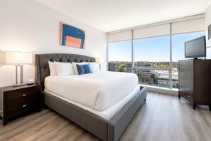 Ein modernes Hotelzimmer mit einem großen Bett, einem Nachttisch, einer Kommode und einem Fernseher.