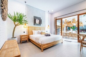 A modern bedroom with a wooden bed, a large window, and a dining area with wicker furniture.