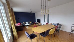 Une pièce spacieuse comprenant une table à manger en bois, plusieurs chaises, un canapé et un téléviseur.