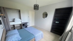 Une chambre avec deux lits, une armoire, un miroir et un luminaire suspendu.