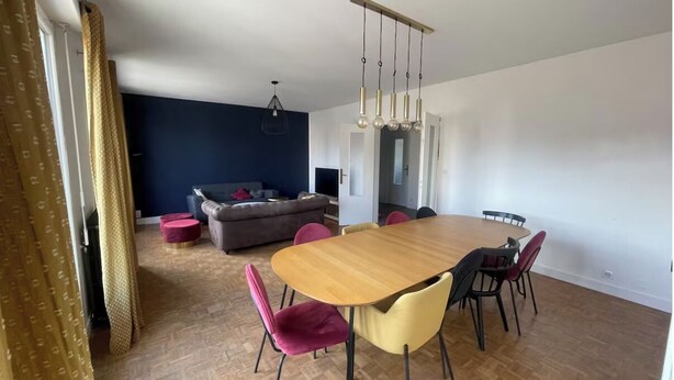 Un coin repas avec une table et des chaises en bois, un canapé et un luminaire suspendu.