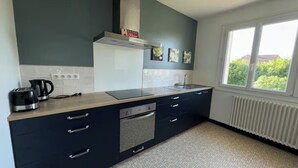 Une cuisine moderne avec un plan de travail foncé, un four encastré et une fenêtre donnant sur la verdure à l’extérieur.