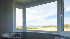 A corner room with a large bay window overlooking a rural landscape. - Chynoweth (Newquay)