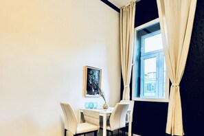 A dining area with a table, chairs, a vase, and a window with curtains.